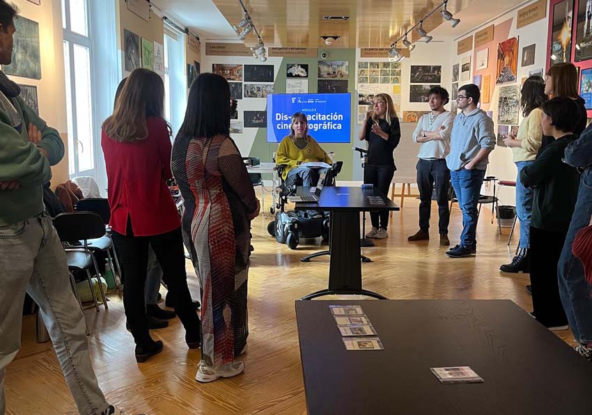 Group of people listening to a woman in a wheelchair